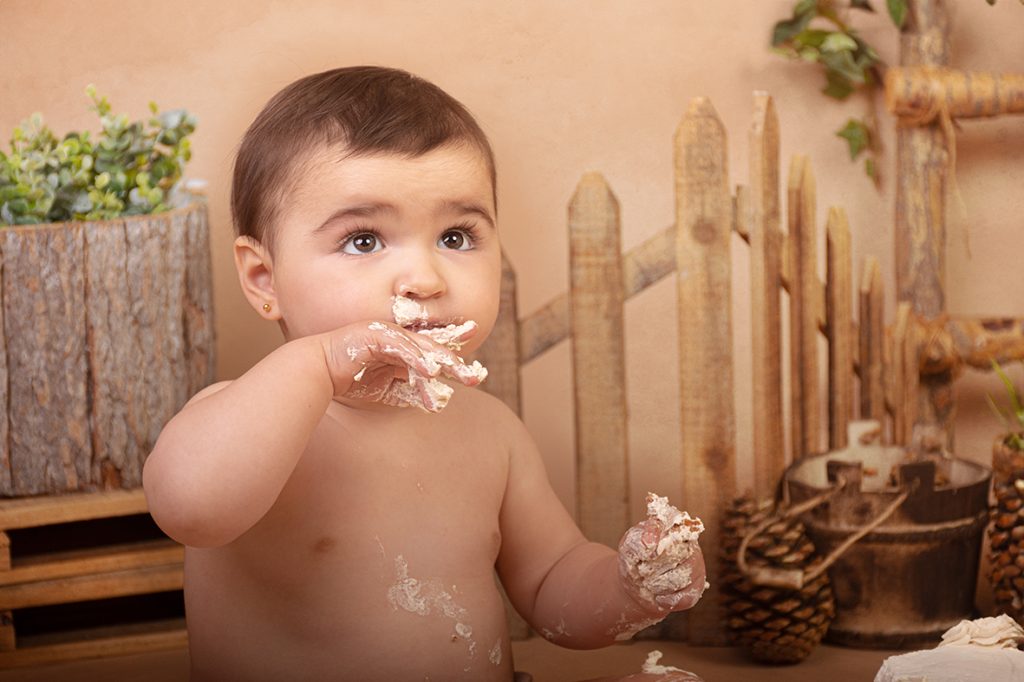 Bebé lamiendo sus dedos manchados de tarta